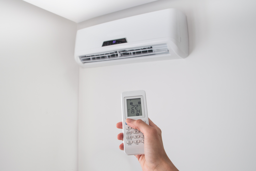 A person using a remote control to set up the temperature of the heat pump unit
